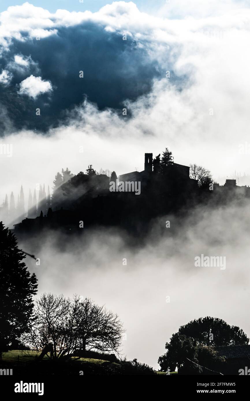 Silhouetted village of Montefioralle in early morning mist as sun breaks through, Tuscany, Italy, Europe Stock Photo