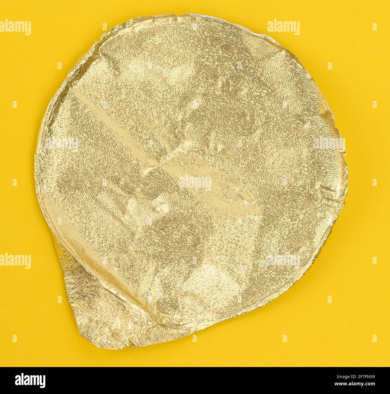 round golden aluminum thin lid for plastic yogurt jars on a yellow