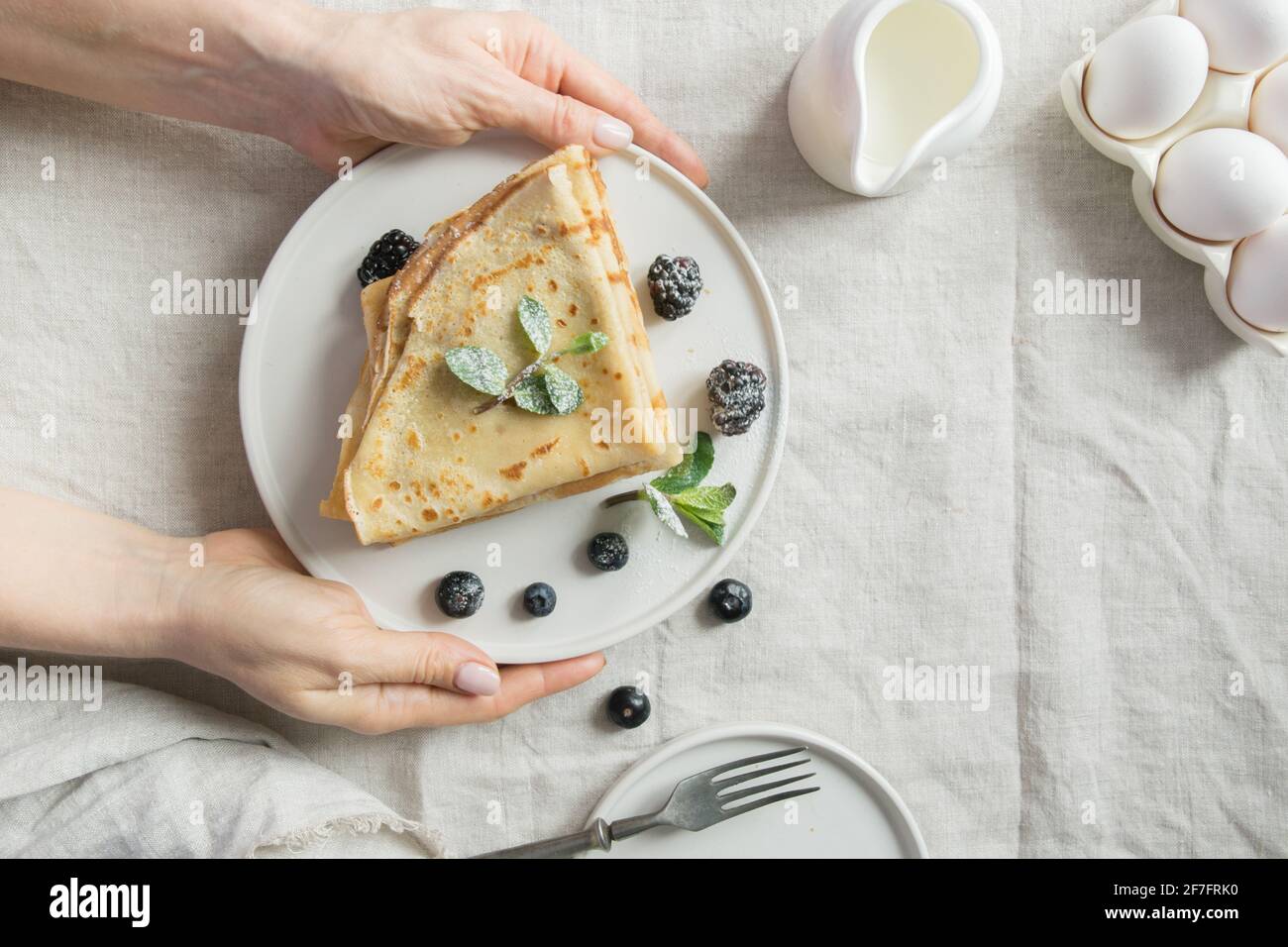 Woman served breakfast of tasty Russian pancakes or blini. View from above. Stock Photo