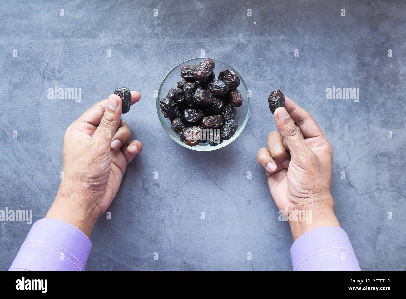 man hand eating fresh date fruit in a bowl on table  Stock Photo