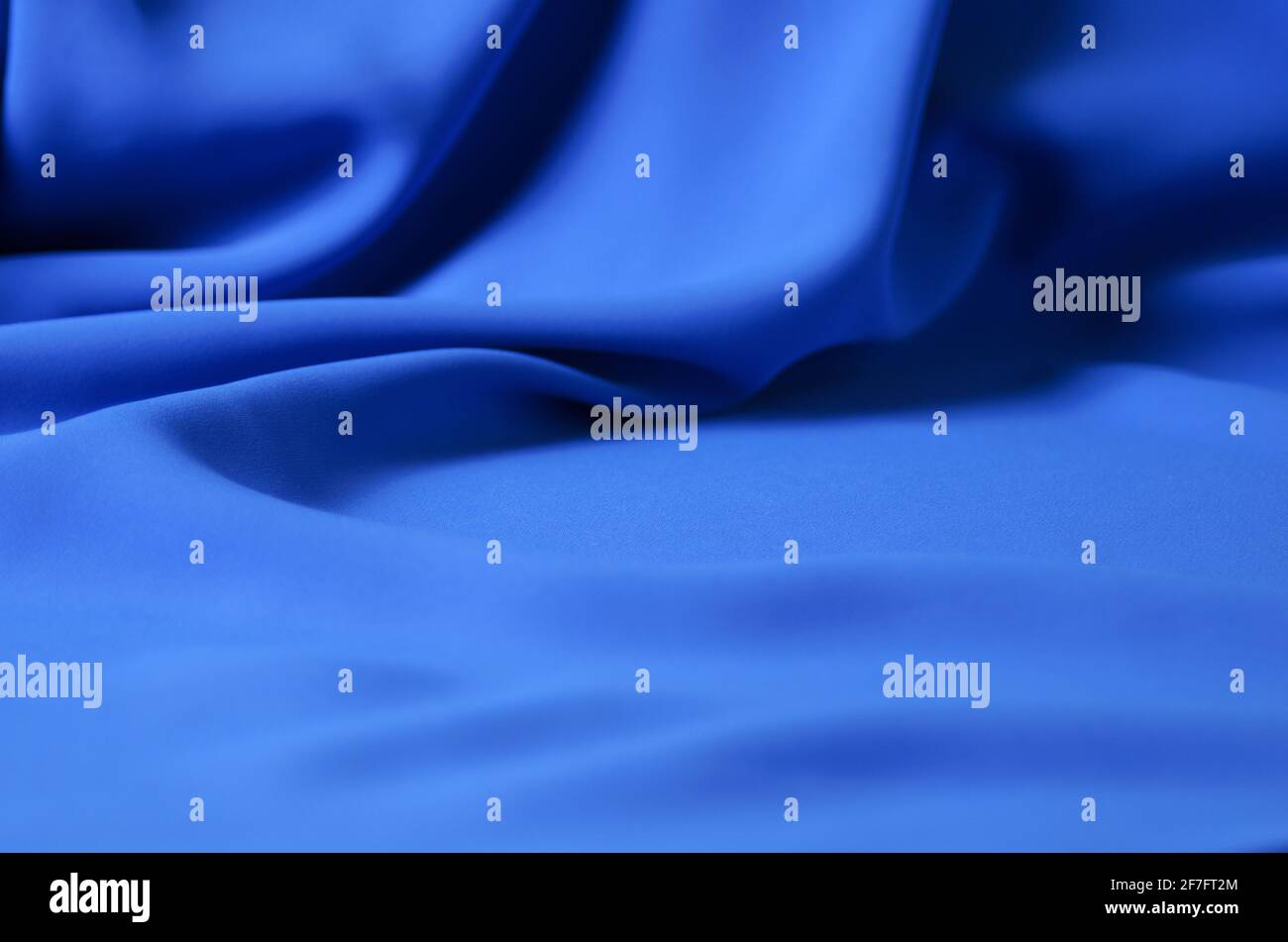 The blurred, defocus background is made of a delicate blue chiffon fabric with folds in the form of waves. Selective focus. Stock Photo