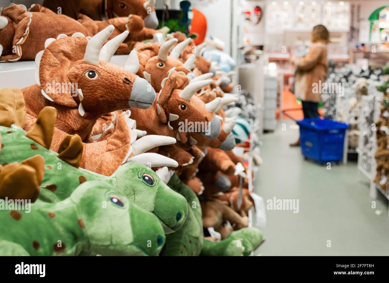 Close-up of toy dinosaurs on store shelves. Blurry shoppers in the background. Stock Photo