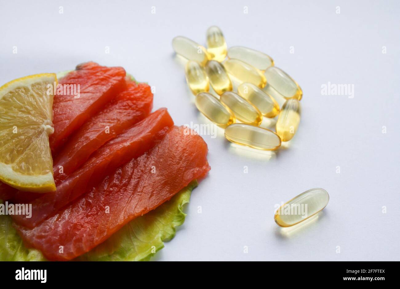 Omega-3 fish oil capsules in the form of fish and salmon fillet slice with lemon and lettuce leaf. Stock Photo