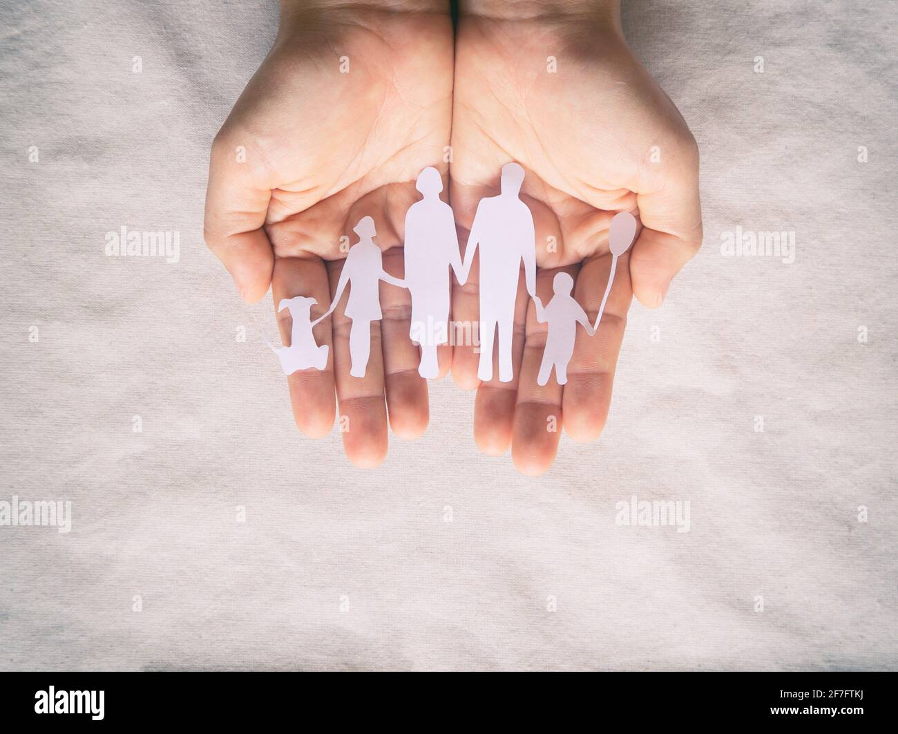 Hand holding family paper cut on fabric background. Family day concept, foster care, domestic violence, homeschool, international day of families, wor Stock Photo