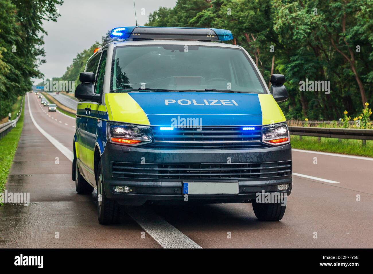 Police car from Germany from the state of Brandenburg on the autobahn. Switched on blue light and warning lights on the vehicle. Two-lane carriageway Stock Photo