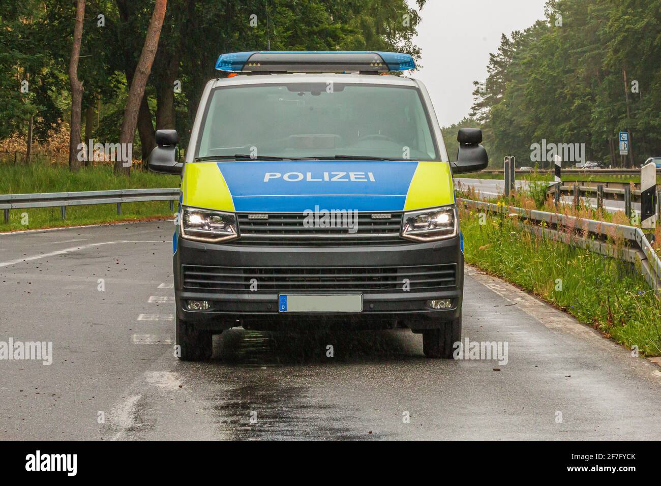 Police car on the highway. Front view of a vehicle from the state of Brandenburg in a parking lot. Asphalt roadway of an emergency stop. Trees, lane Stock Photo