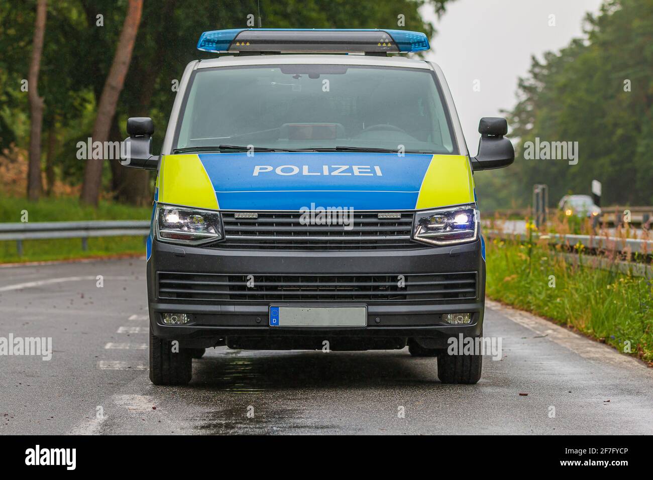 Front view of a police car on the highway with the lights on. Vehicle from the state of Brandenburg in a parking lot. Asphalt roadway of an emergency Stock Photo