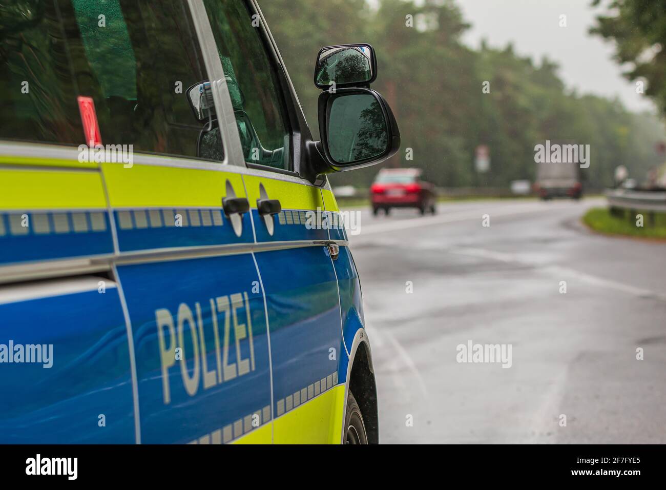 Police car from the side. Passenger's side with police writing on the body. Highway in the background. Mirror window body from the passenger side with Stock Photo