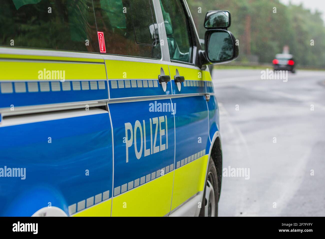 German police car on the highway from the side. Vehicle body on the passenger side with doors, mirrors and lettering Police with yellow and blue paint Stock Photo