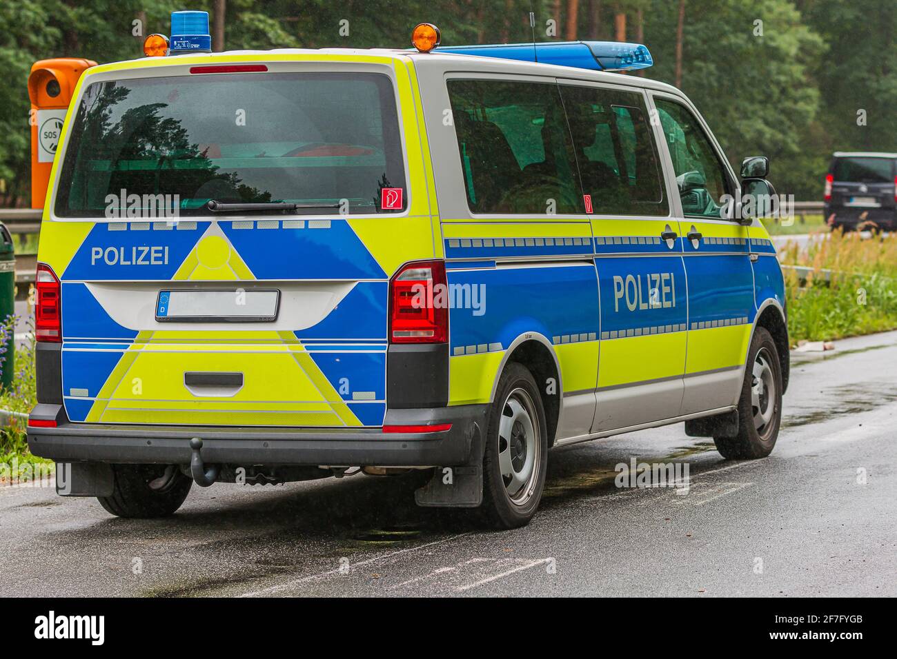 German police car in an emergency stop on the highway next to an emergency telephone. Rainy weather and wet road surface. View of the vehicle body Stock Photo