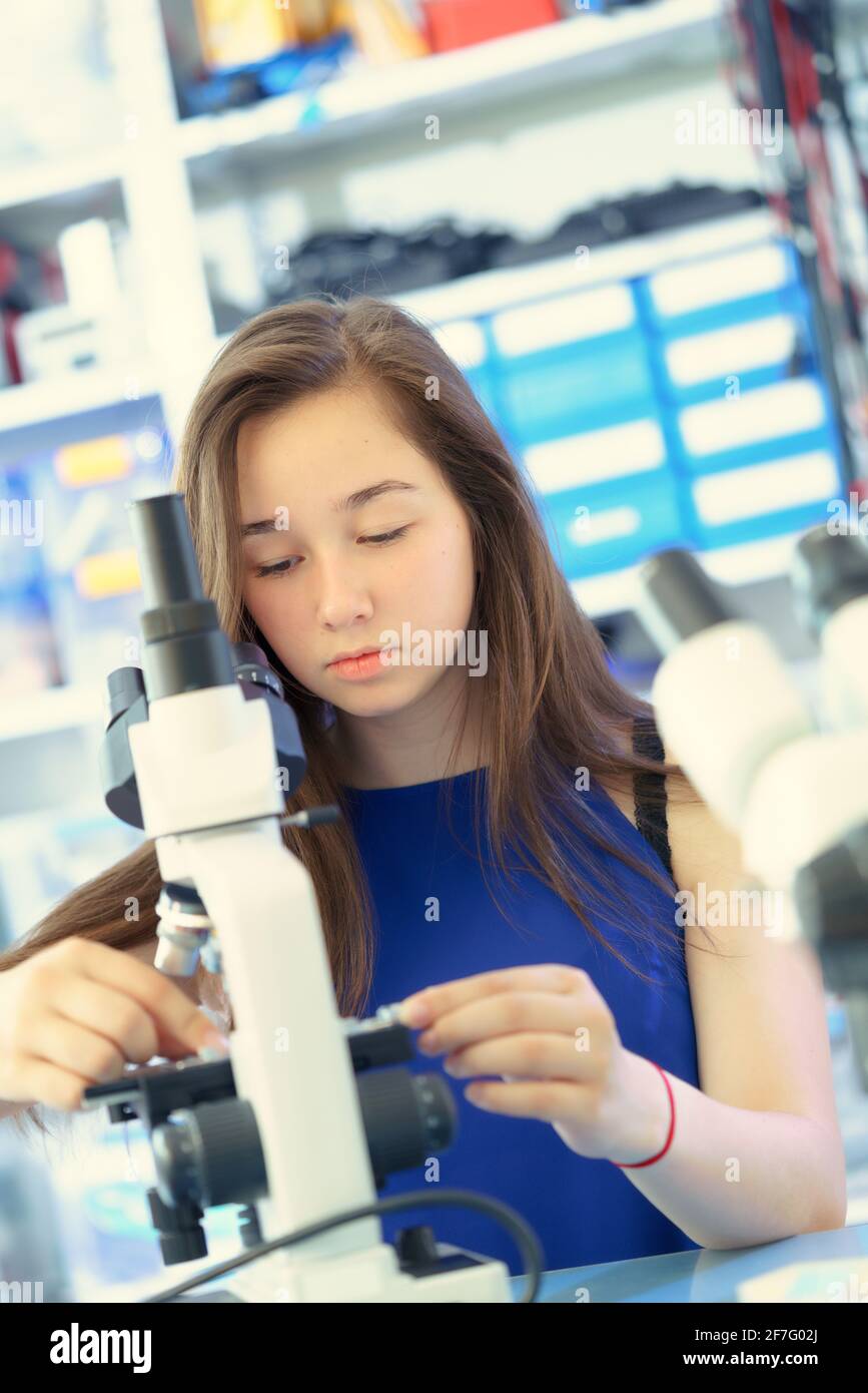 Schoolgirl girl with a microscope in the laboratory. Binocular microscope in a school laboratory Stock Photo