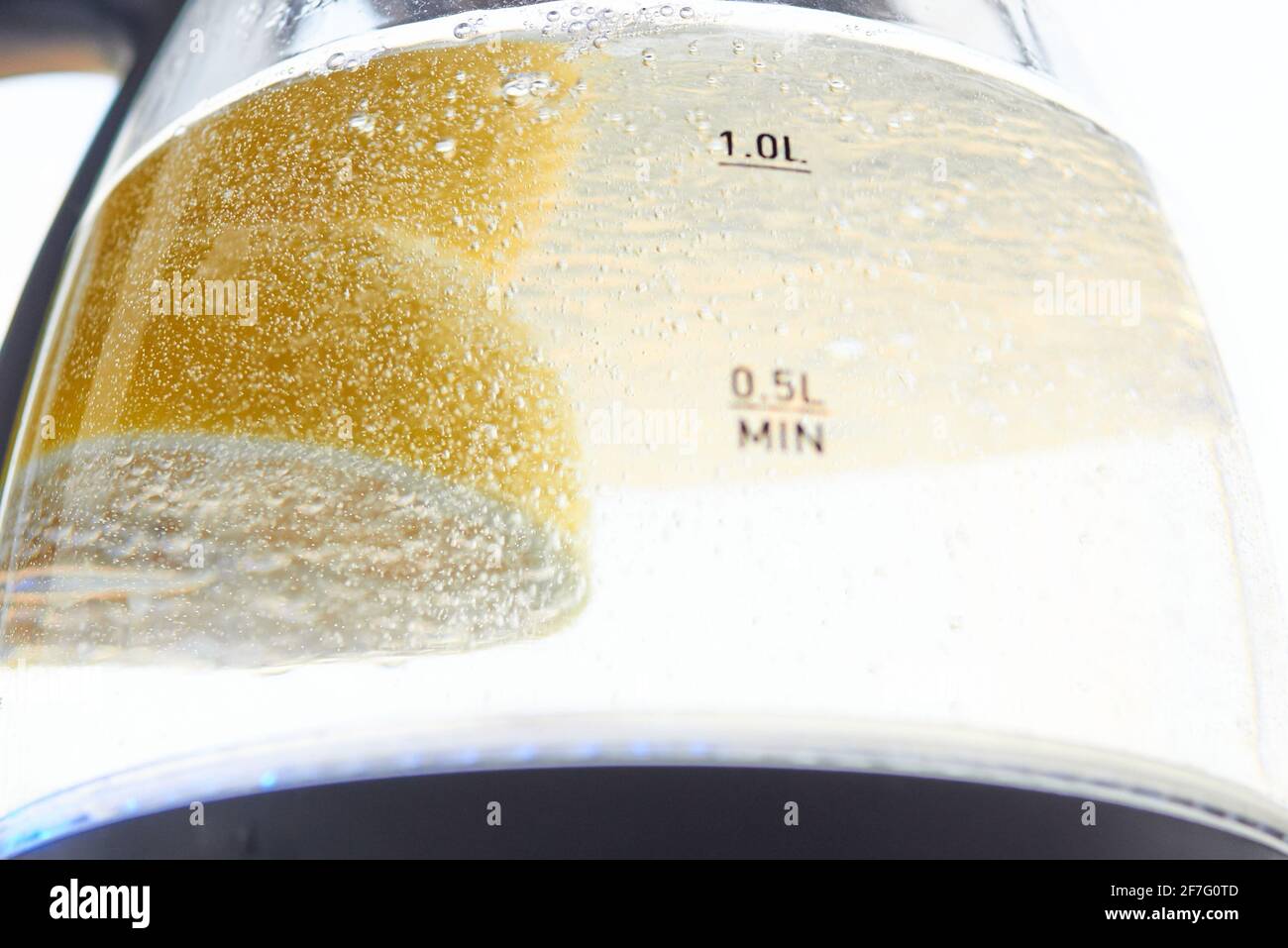 Half a yellow lemon is boiled in a glass electric kettle for descaling