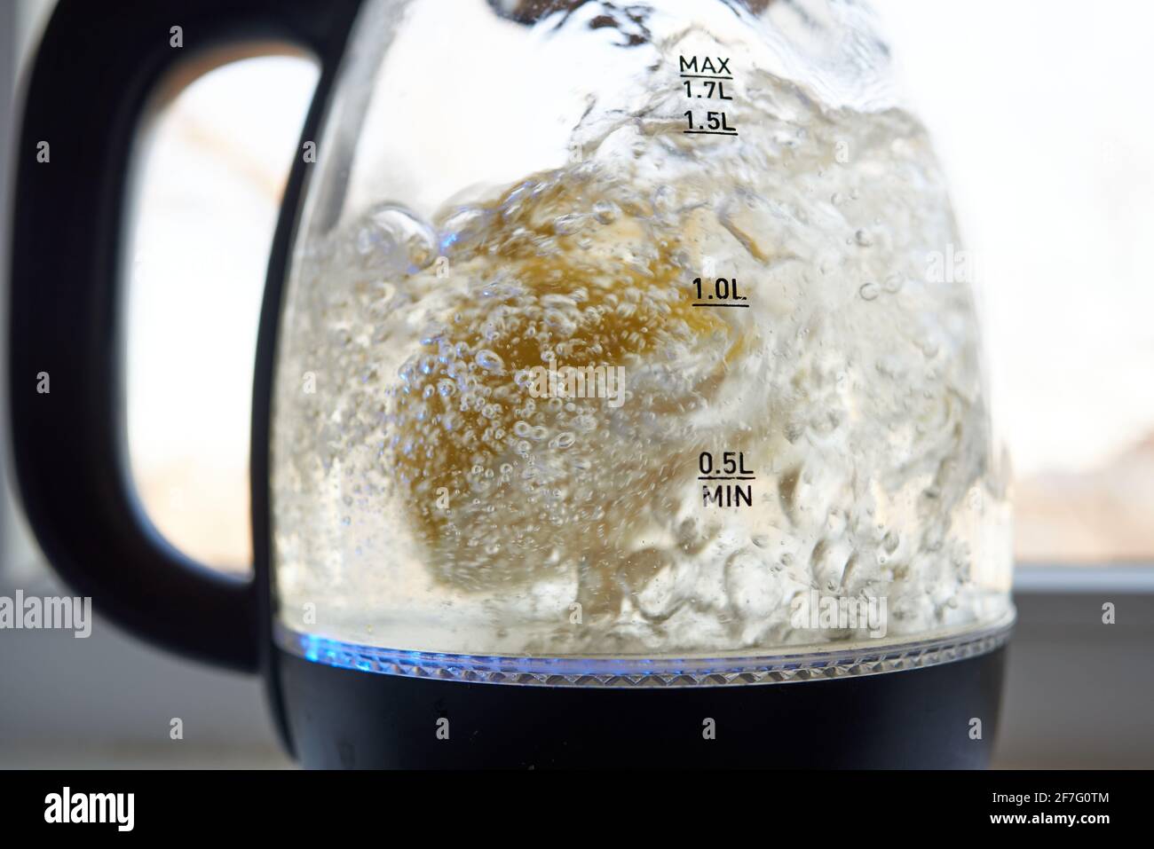 Half a yellow lemon is boiled in a glass electric kettle for descaling