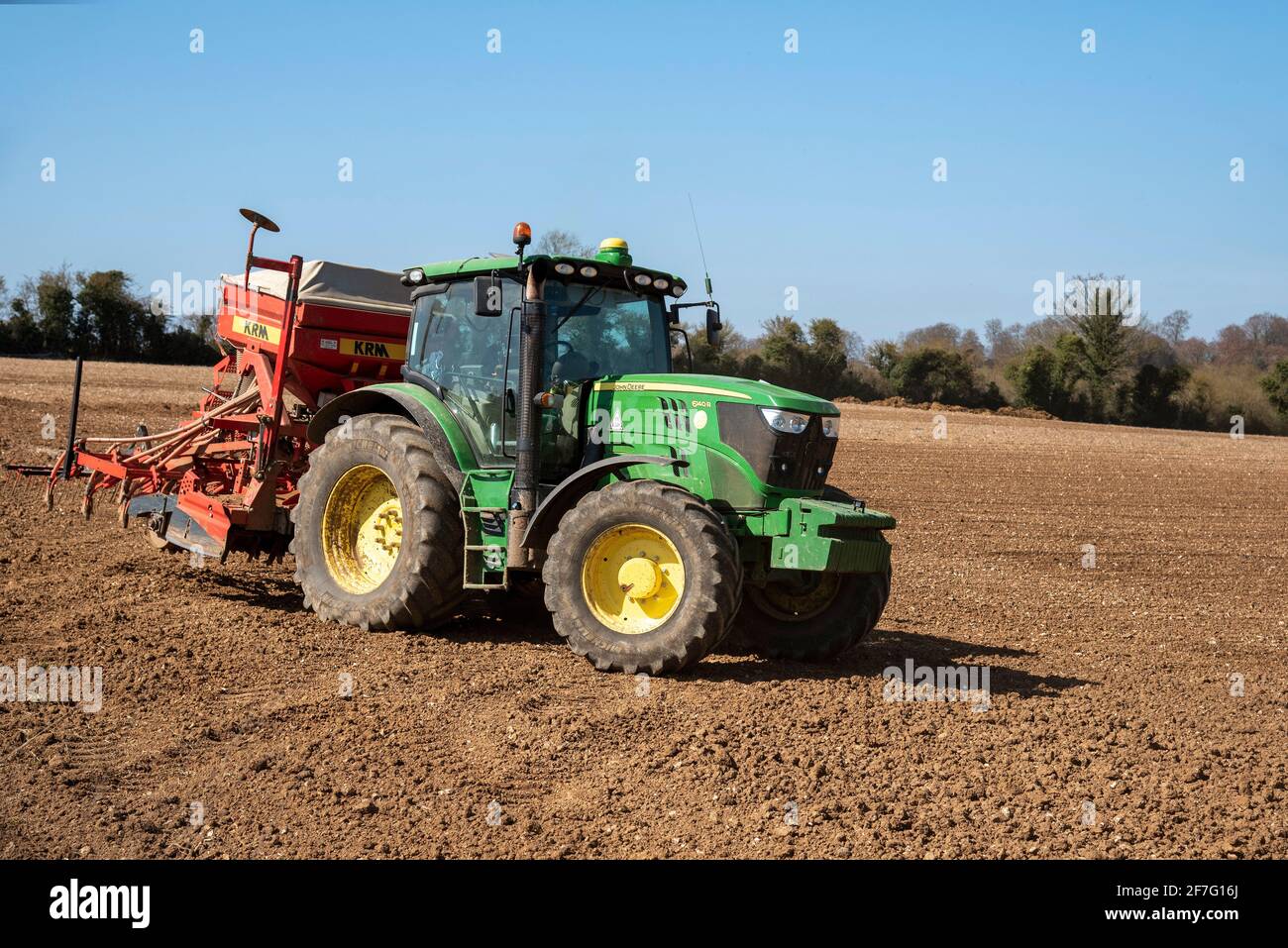 Hampshire, England, UK. 2021. Green tractor with seed drill and