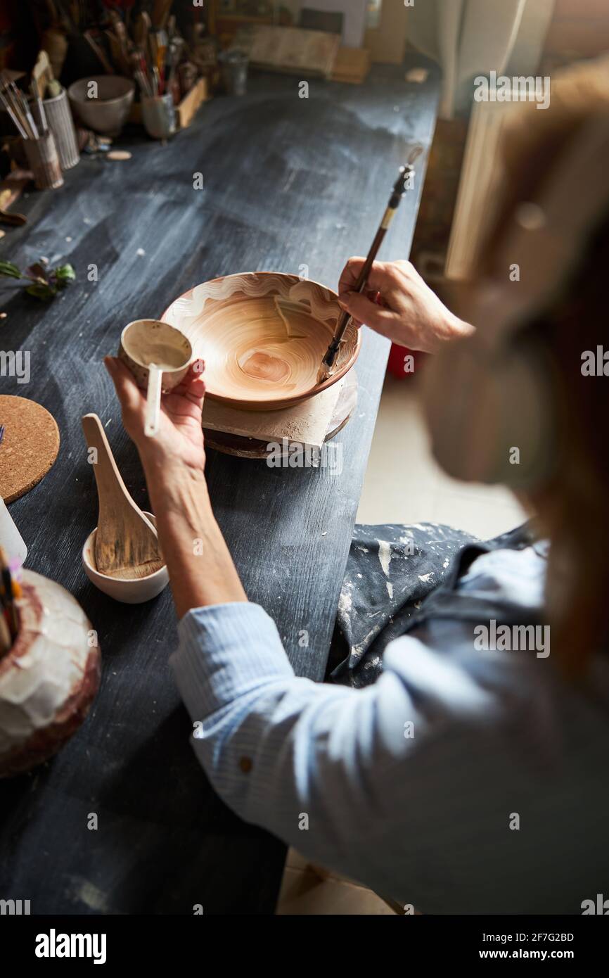 Senior woman ceramist painting pottery in workshop Stock Photo - Alamy