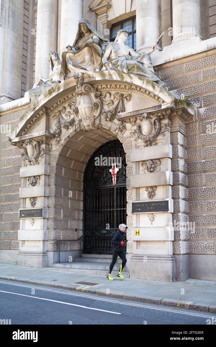 Jogger runs past an imposing entrance to the Old Bailey central criminal court. London, England, UK Stock Photo
