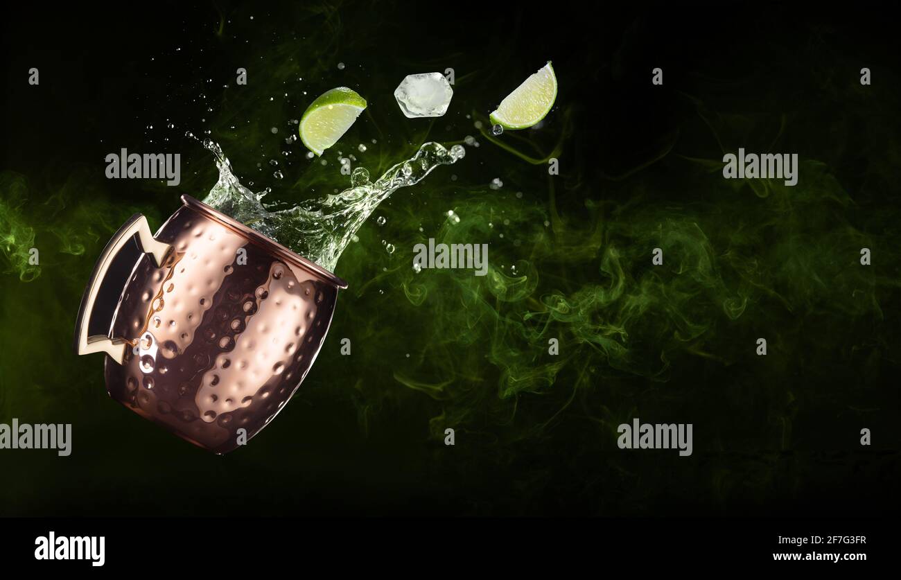 lime and ice falling out of a splashing moscow mule on smoky background Stock Photo