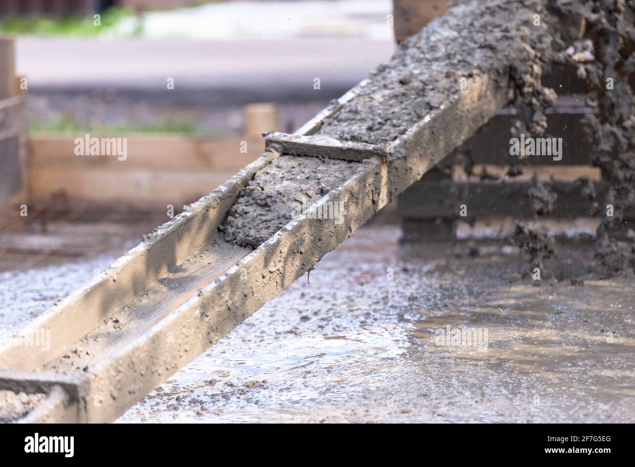 Pouring concrete slabs. The concrete is drained through a makeshift wooden tray from a concrete mixer. Stock Photo