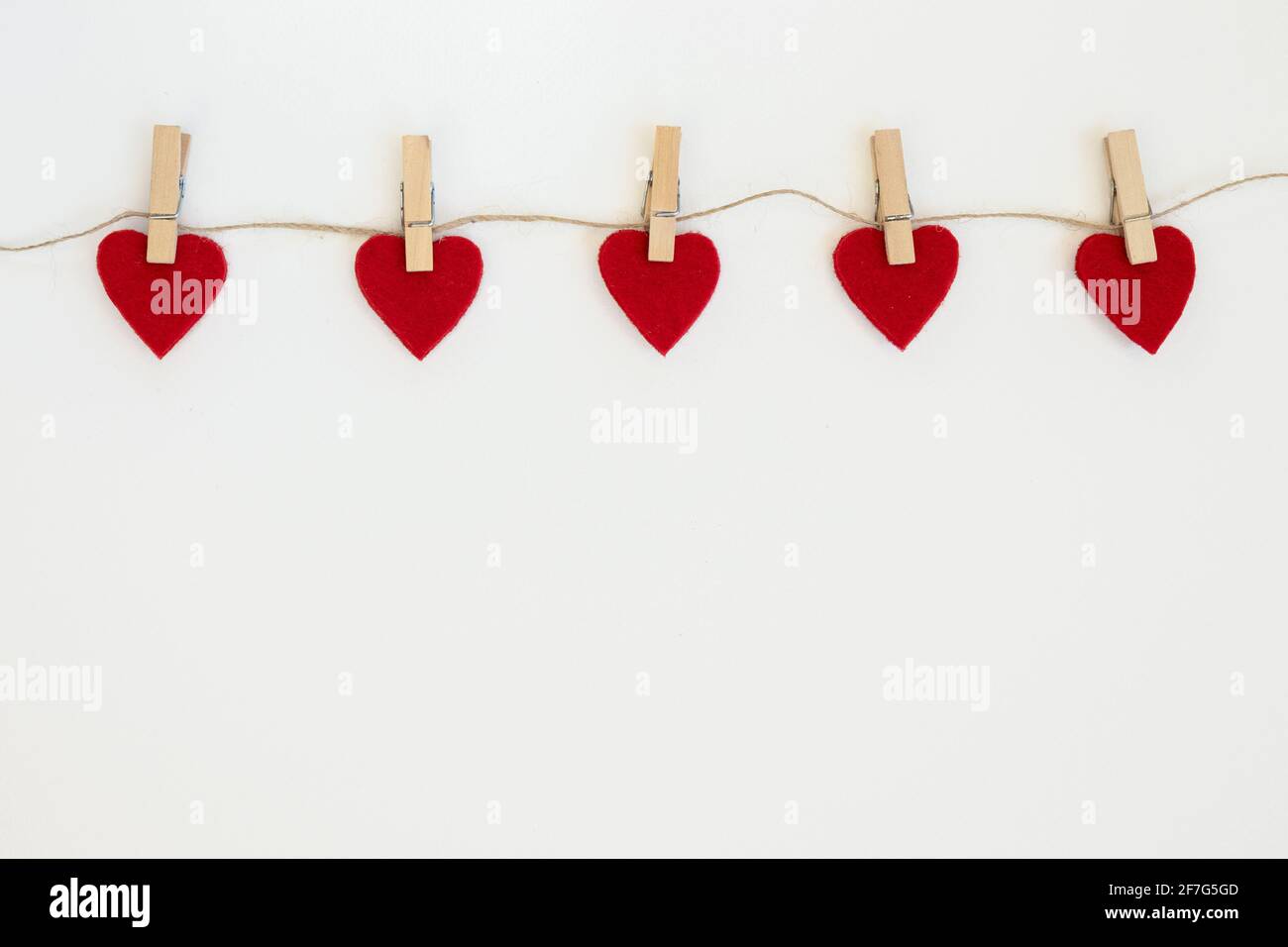 White background with three red hearts on clothespins. Valentine's day card. Stock Photo