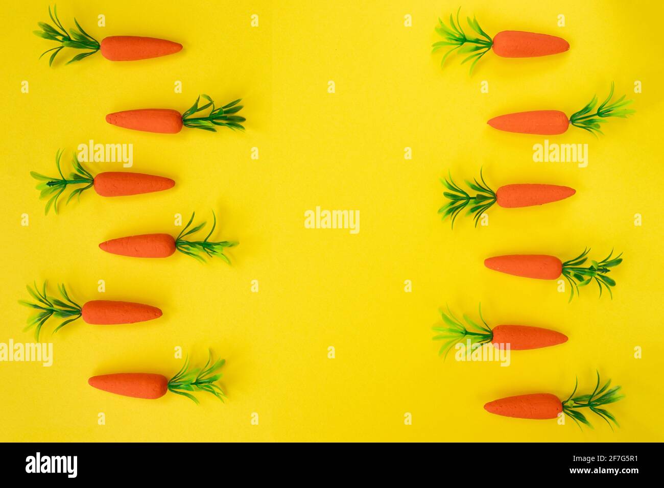 Easter pattern made with carrots on bright yellow background. Minimal Easter composition. Flat lay. Stock Photo