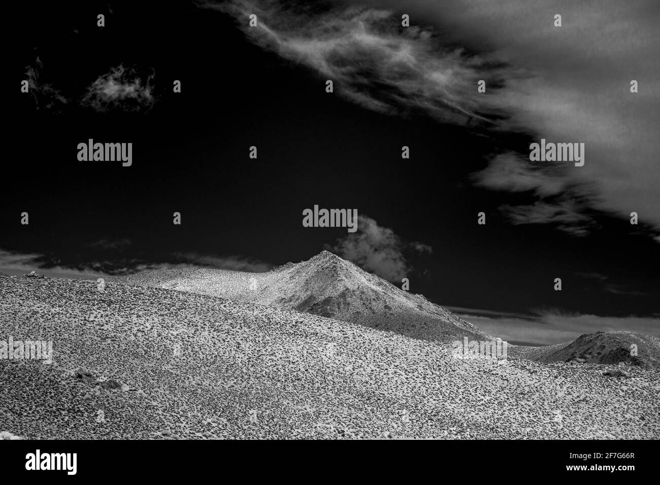 Barren hills and mountains under black skies with white clouds. High contrast black and white image. Stock Photo