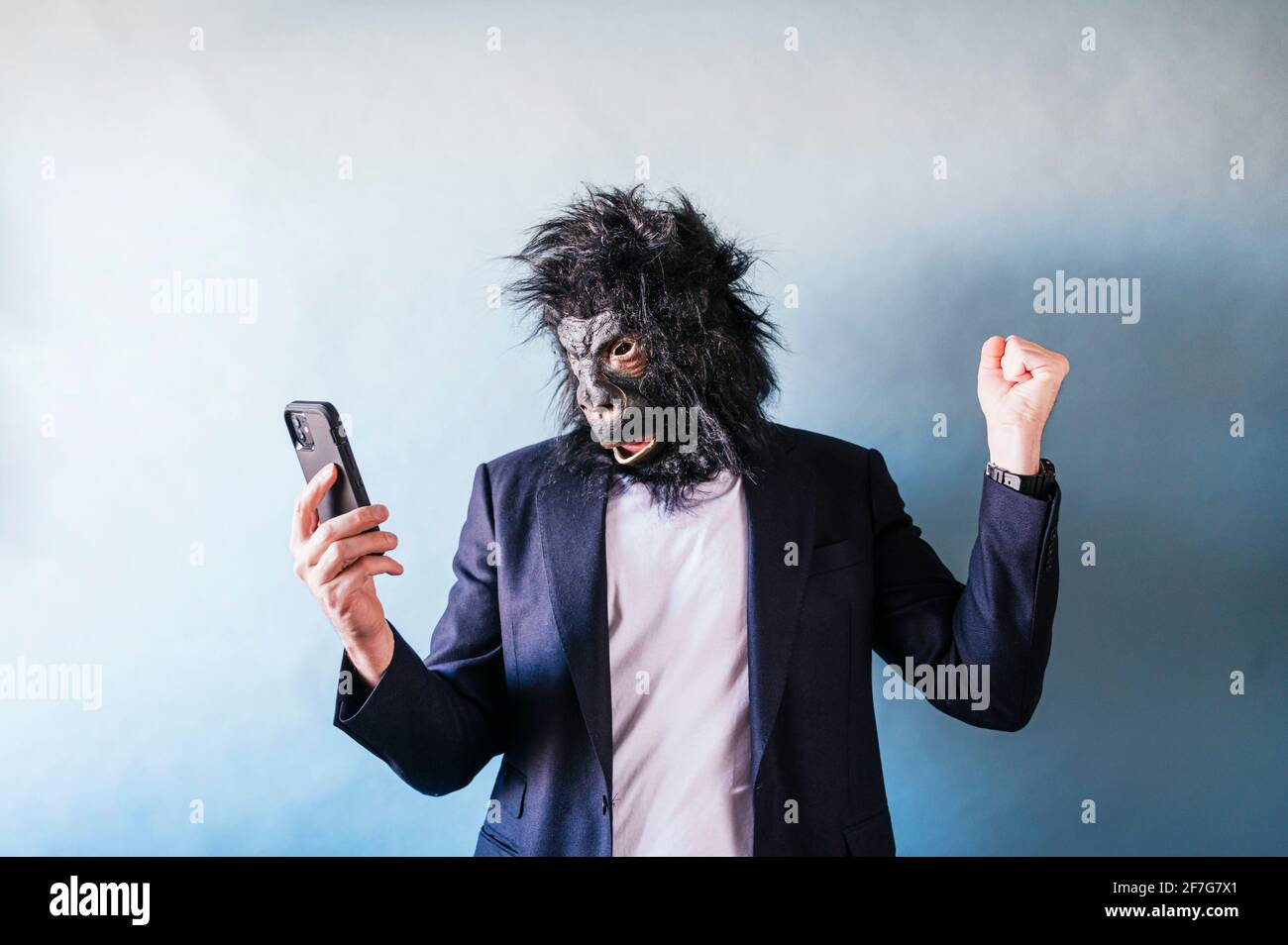 Man in gorilla mask euphoric using smart phone Stock Photo