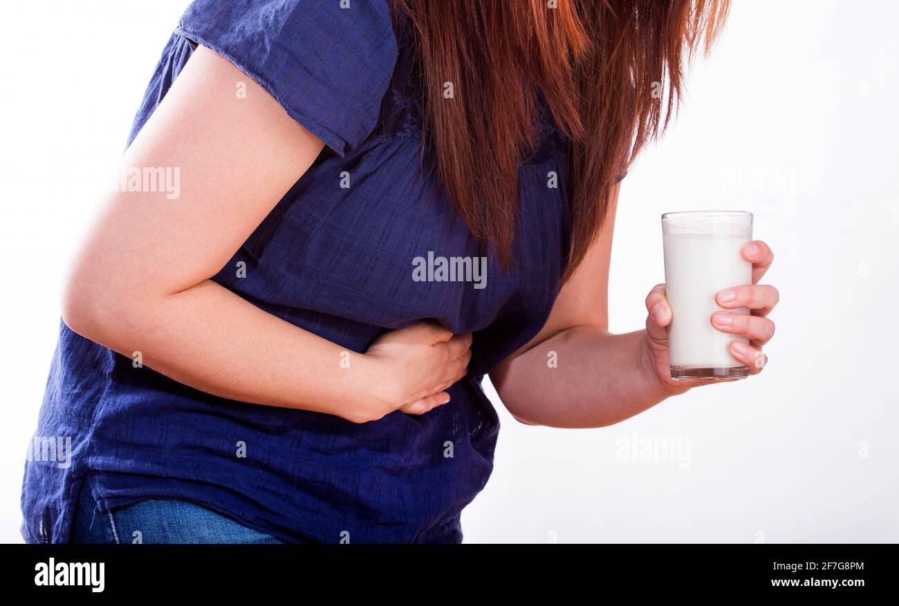 Woman with stomach pain holding a glass of milk. Lactose intolerance