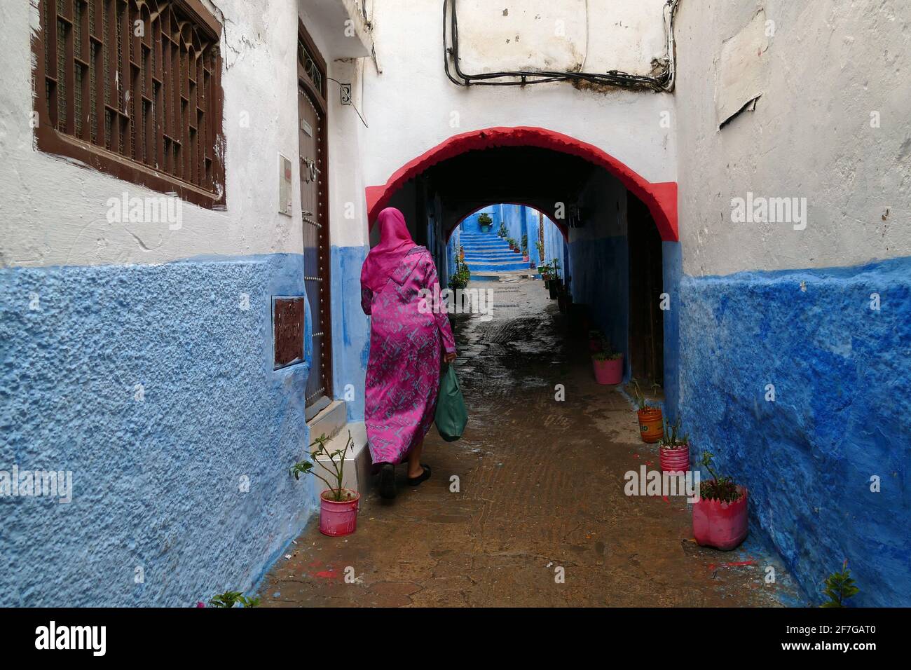Woman with pink dress walking in a little colorful alley in the medina of Tetouan, North of Morocco, Africa Stock Photo