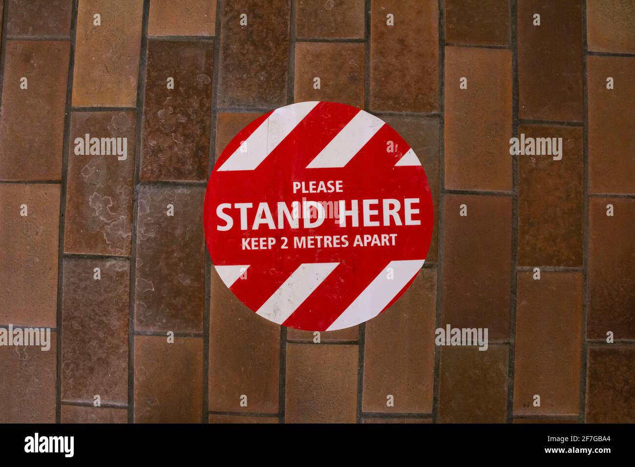 London, Ontario, Canada - February 6 2021: A floor sign near Sherwood Forest Mall's library asks patrons to stand six feet apart from others in line. Stock Photo