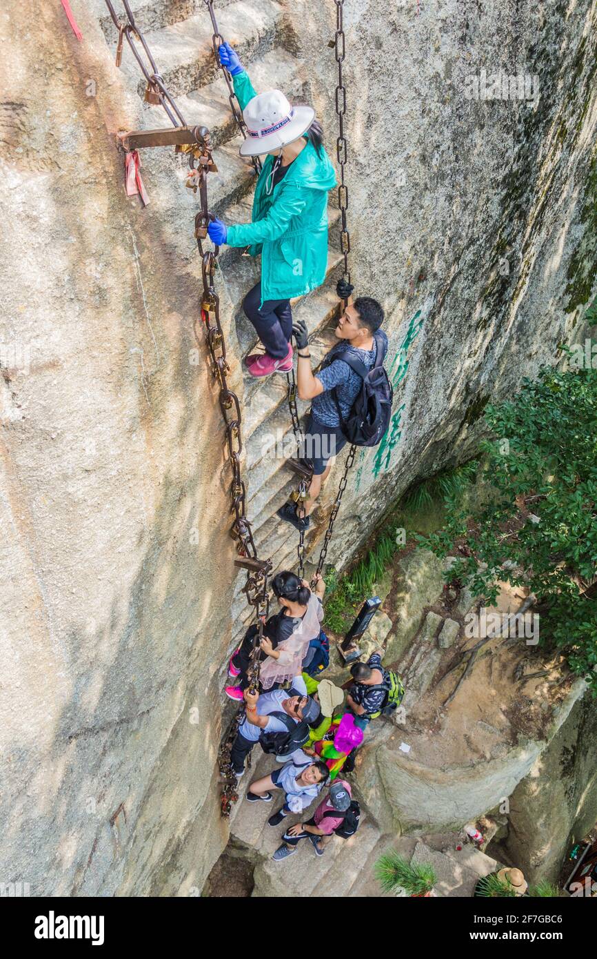 HUA SHAN, CHINA - AUGUST 4, 2018: People climbing steep stairs leading to the peaks of Hua Shan mountain in Shaanxi province, China Stock Photo