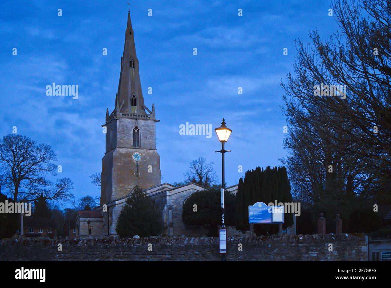 Sharnbrook village, Bedfordshire, England, UK - St Peter's Church in the early hours of the morning while still dark and streetlamp is lit Stock Photo