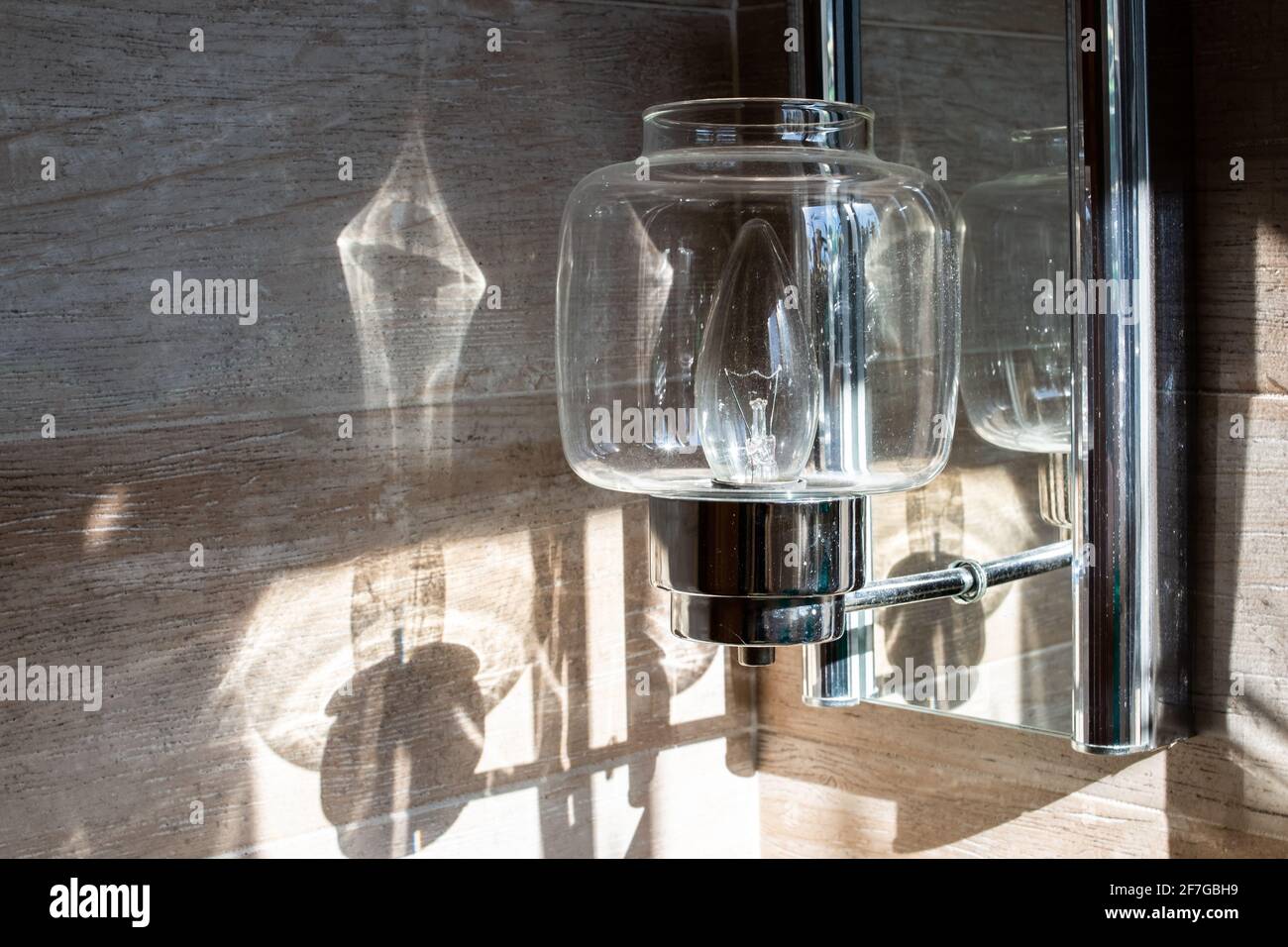 Photo of a clear glass light fixture reflecting sunlight on the wall in a bathroom interior in London, Ontario, Canada. Stock Photo