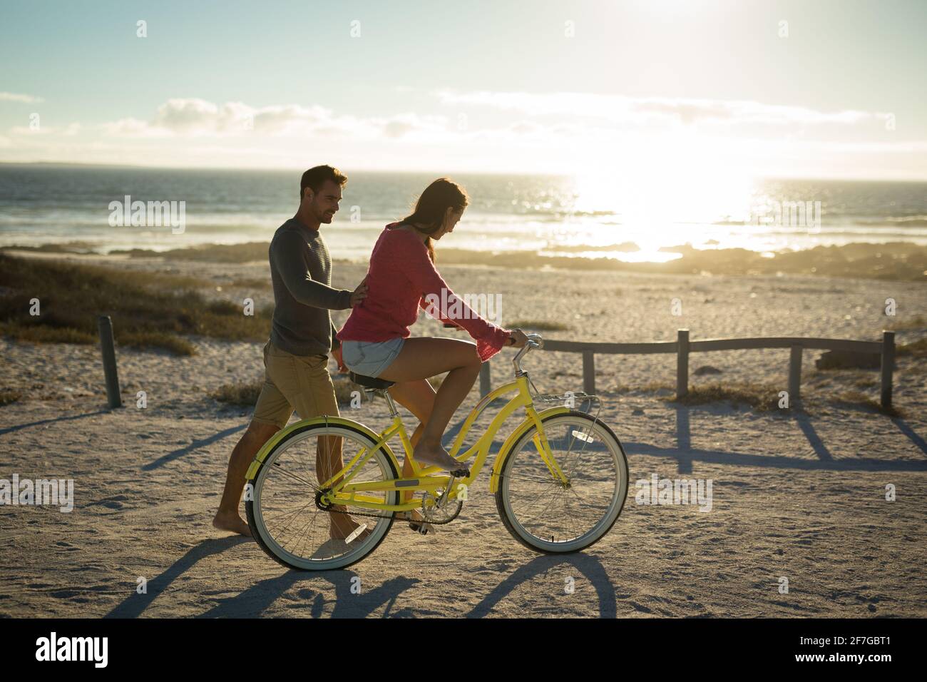 Happy caucasian couple at the sea learning to ride bicycle Stock Photo