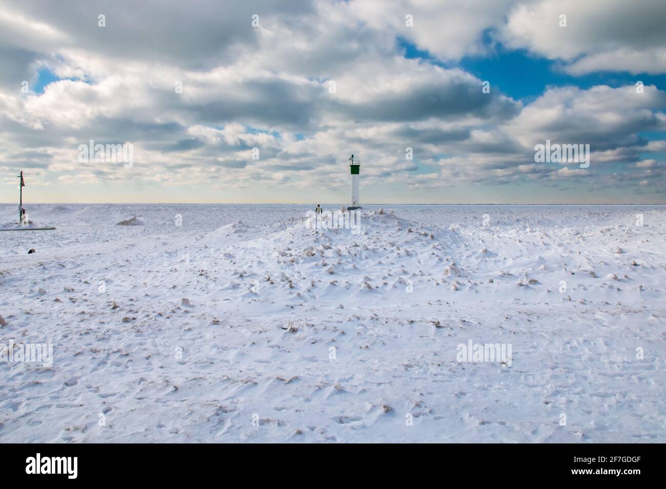 Grand Bend, Ontario, Canada - A man walks back from the edge of the Grand Bend Pier, where the lighthouse looks out onto a thick carpet of ice. Stock Photo