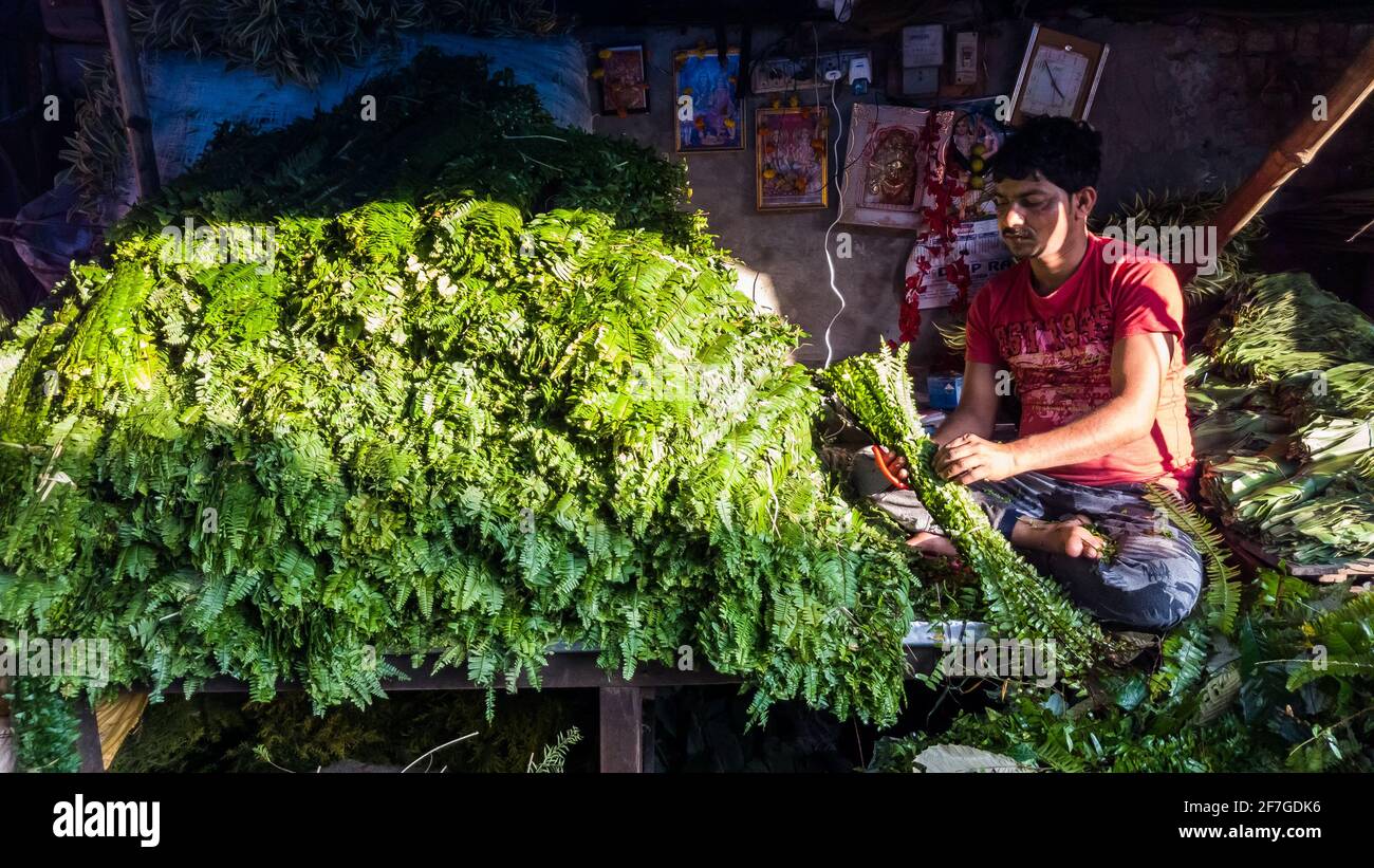 Kolkata, West Bengal, India - January 2018: A street vendor selling green leaves at his roadside stall in the Mullick Ghat flower market in the city o Stock Photo