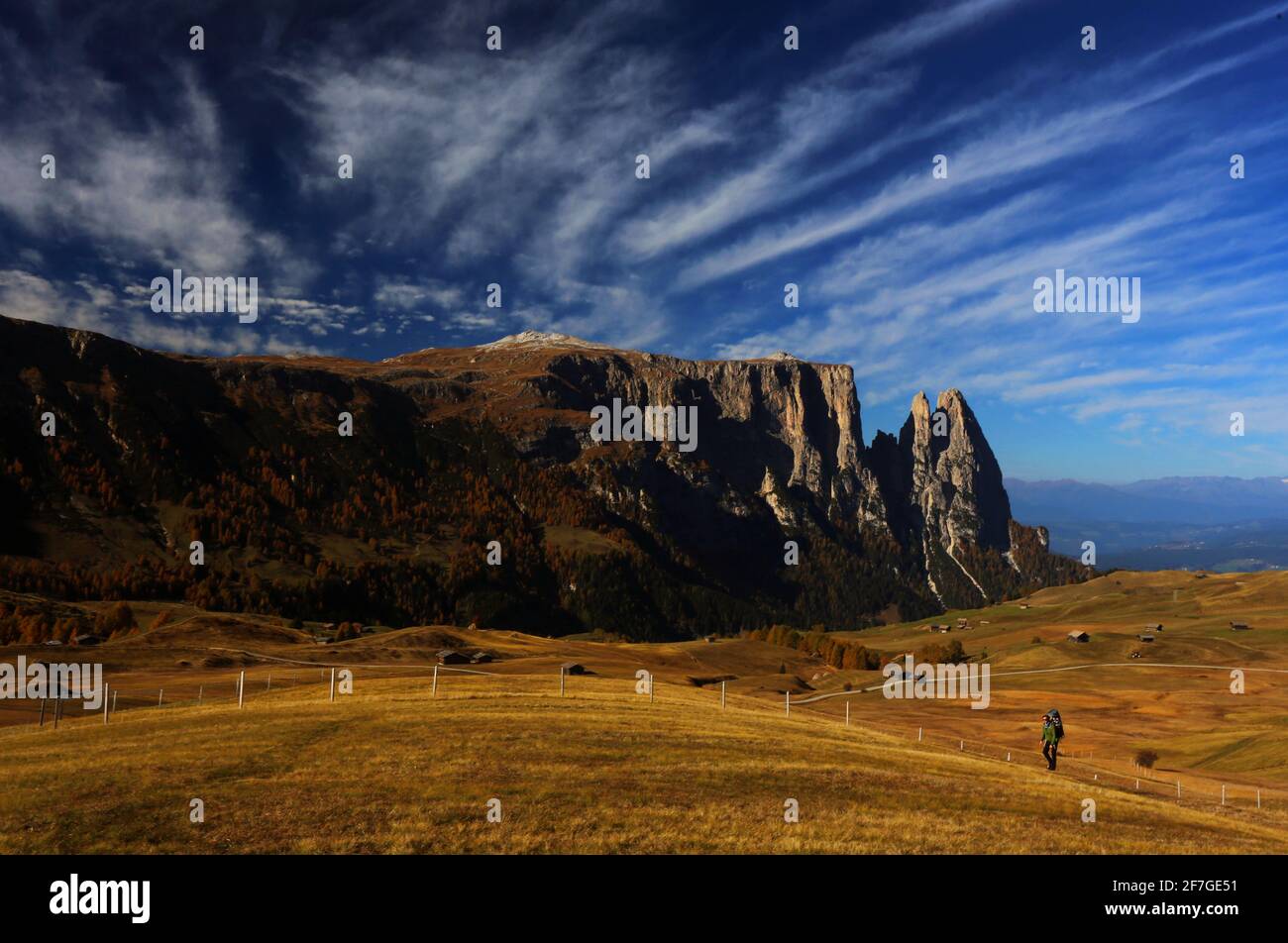 Wanderer auf den Wiesen der Seiser Alm mit Schlern und phantastischer Wolkenstimmung in Südtirol in den Dolomiten in Italien Stock Photo
