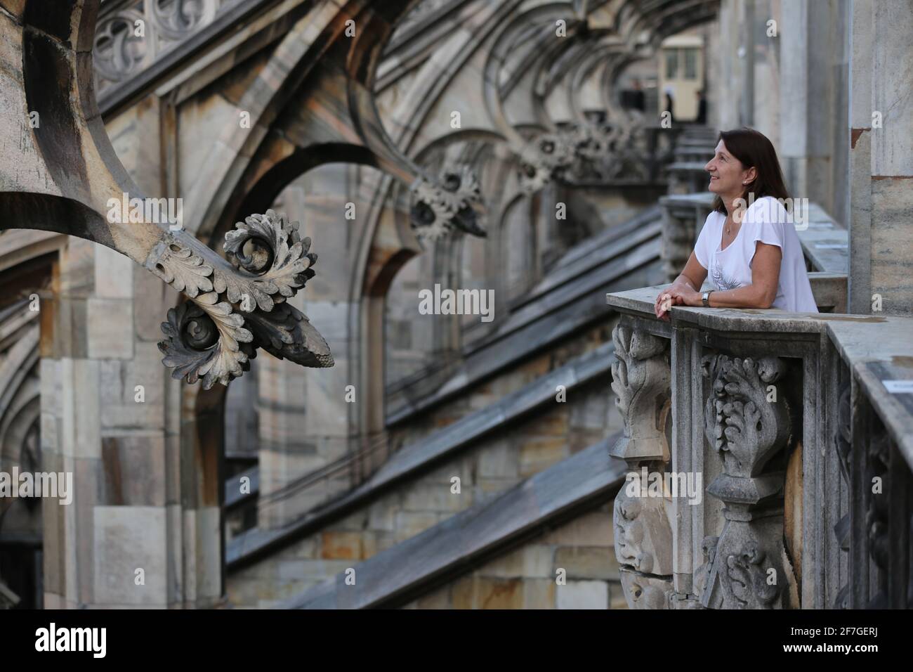 weibliche Touristin auf einem gotischen Balkon zwischen Bögen auf dem Dach des Mailänder Doms in Italien Stock Photo