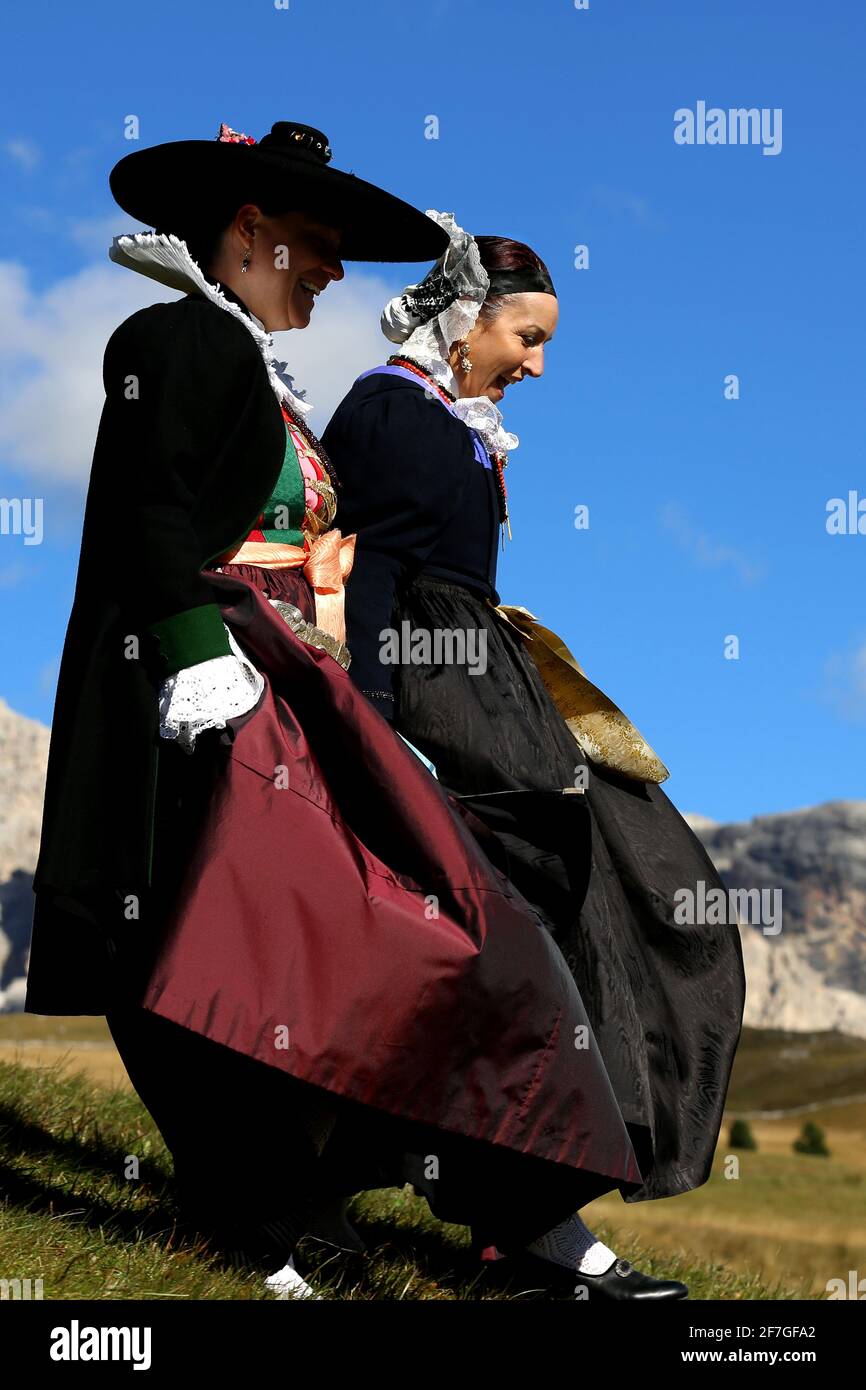 Südtiroler Frauen in traditioneller Grödnertracht unterwegs in den Bergen der Dolomiten zum Besuch eines Festes in der Bergkappelle zum Gottesdienst Stock Photo