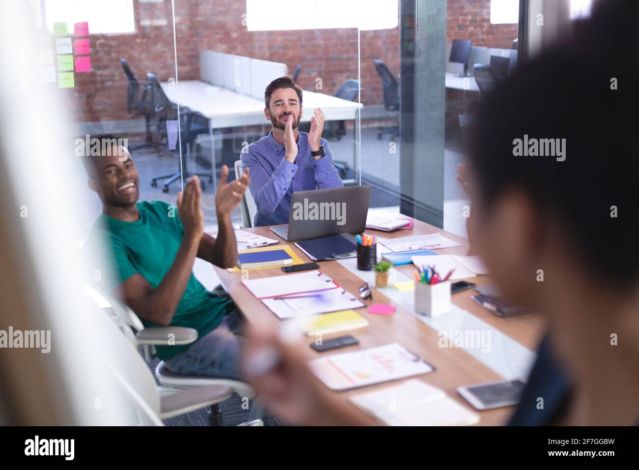 Diverse businessmen applauding presentation of mixed race businesswoman in meeting room Stock Photo