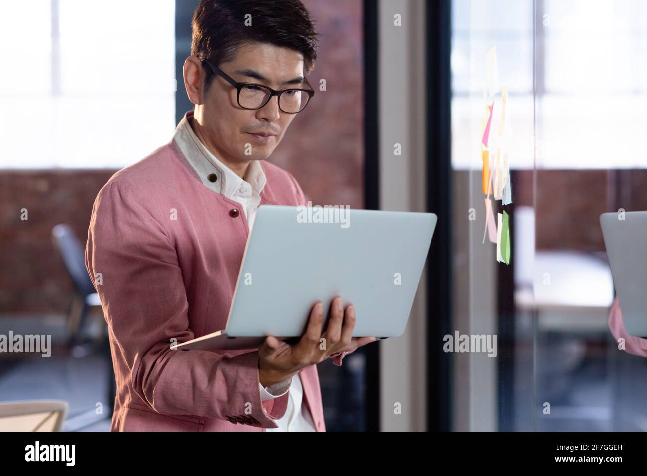 Stylish asian businessman standing and using laptop computer Stock Photo