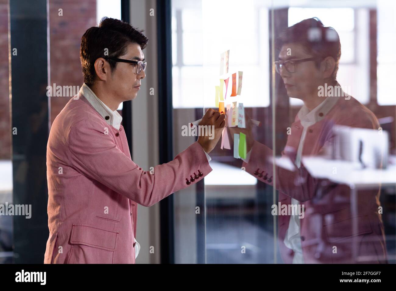 Stylish asian businessman writing notes on glass wall Stock Photo - Alamy