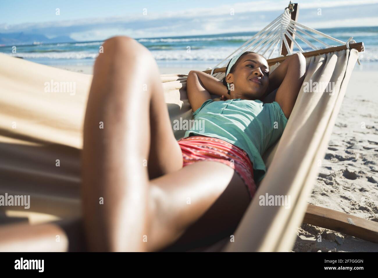 Happy african american woman laying in hammock on the beach Stock Photo