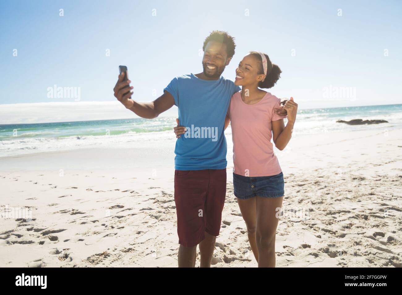 Happy african american couple on beach by the sea taking selfie Stock Photo