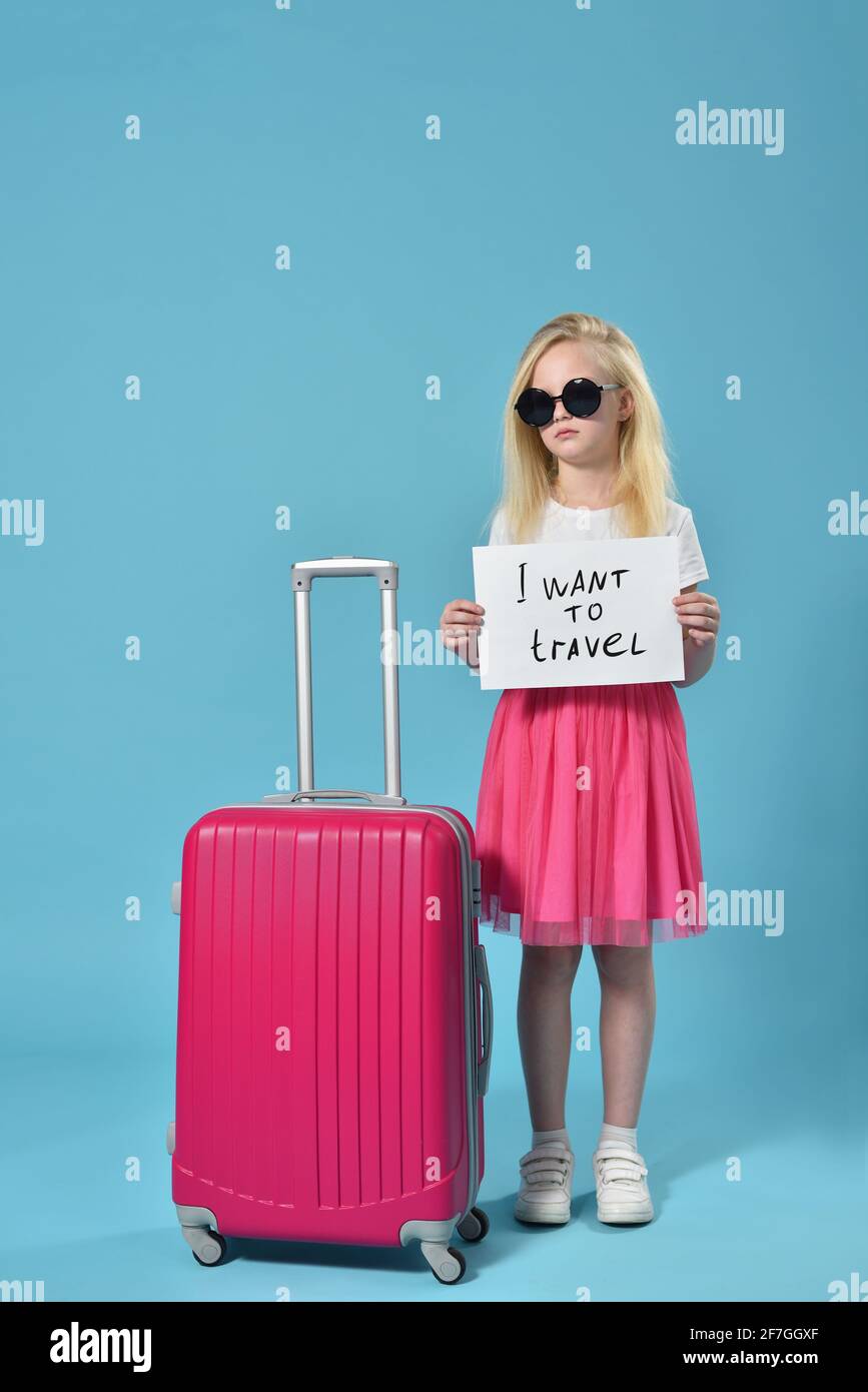 Serious girl child holding a signboard with request i want to travel Stock Photo