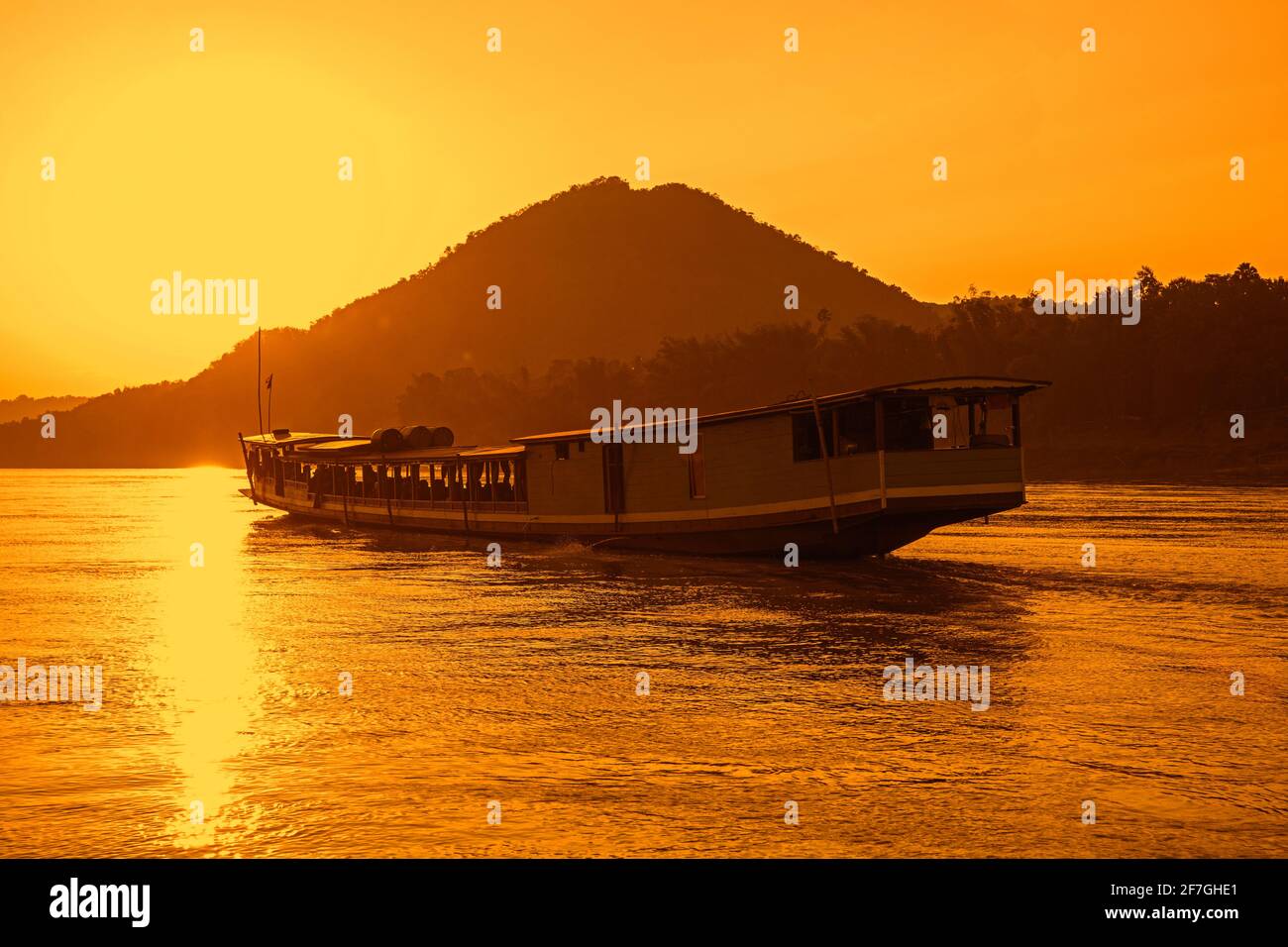 Traditional slowboat / slow boat for river cruise to Luang Phabang / Luang Prabang / Louangphabang on the Mekong River at sunset, Laos Stock Photo