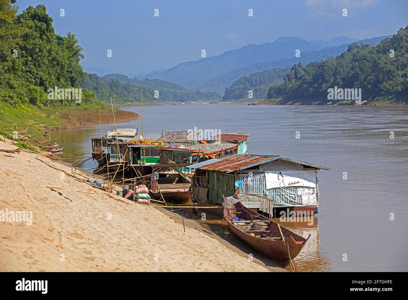 Slowboats / slow boats for river cruises to Luang Phabang / Luang Prabang / Louangphabang on the Mekong River at sunset, Laos Stock Photo