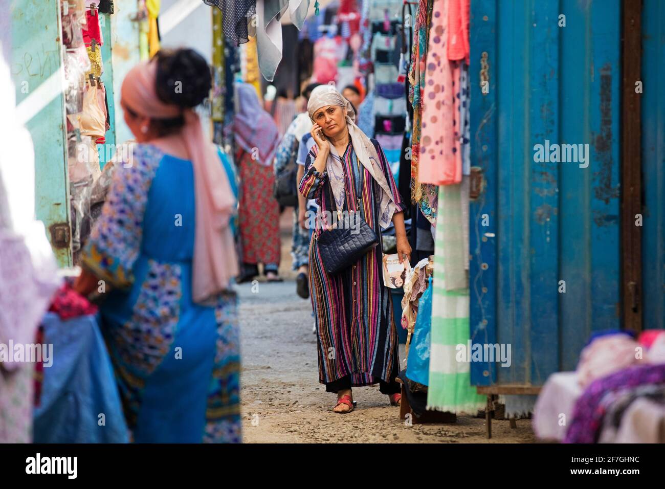 Kyrgyz woman with headscarf calling with smartphone at market in the city Osh, Kyrgyzstan Stock Photo