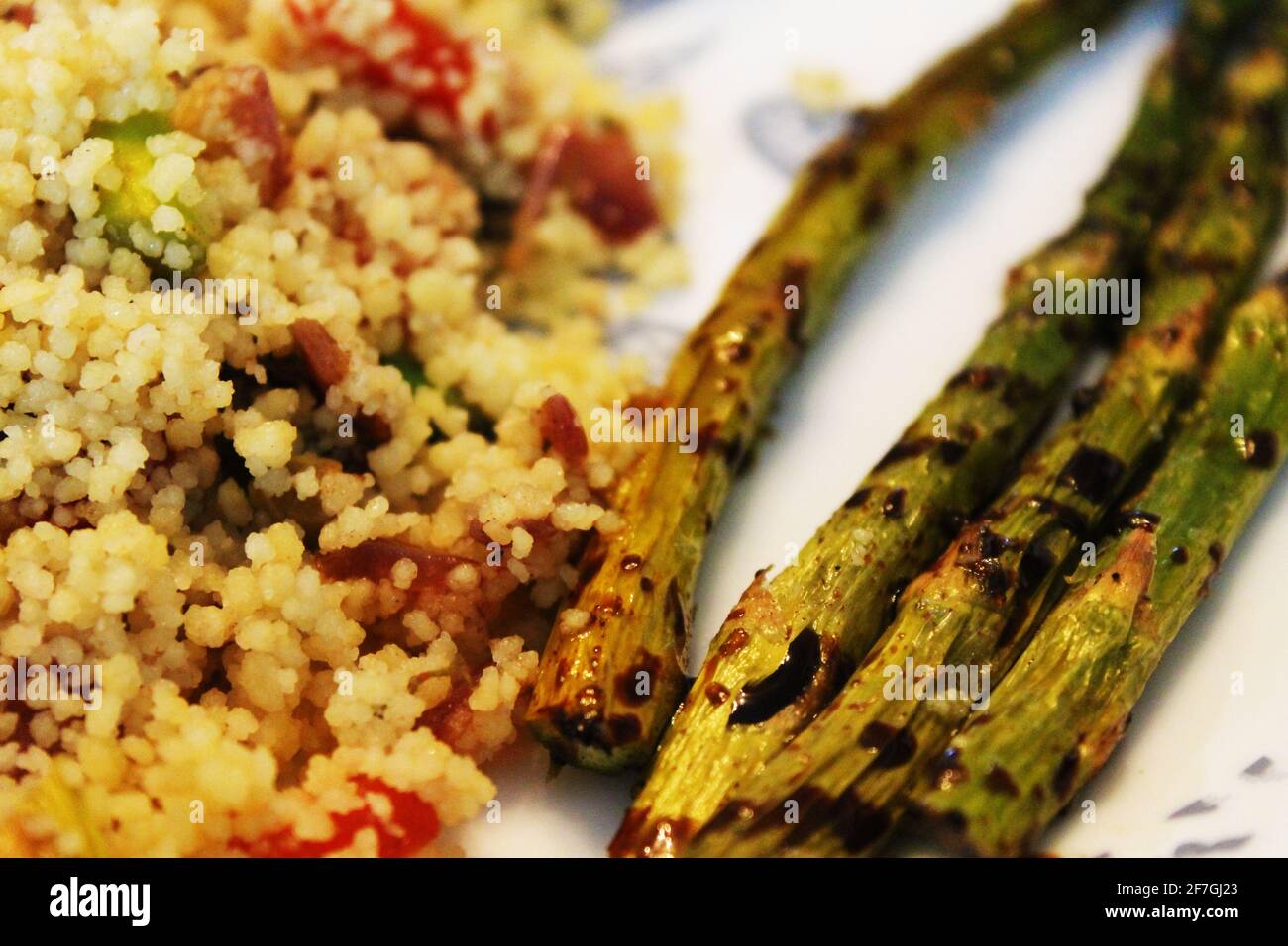 A close-up of a plate of grilled asparagus with a balsamic drizzle and a side of couscous. Stock Photo