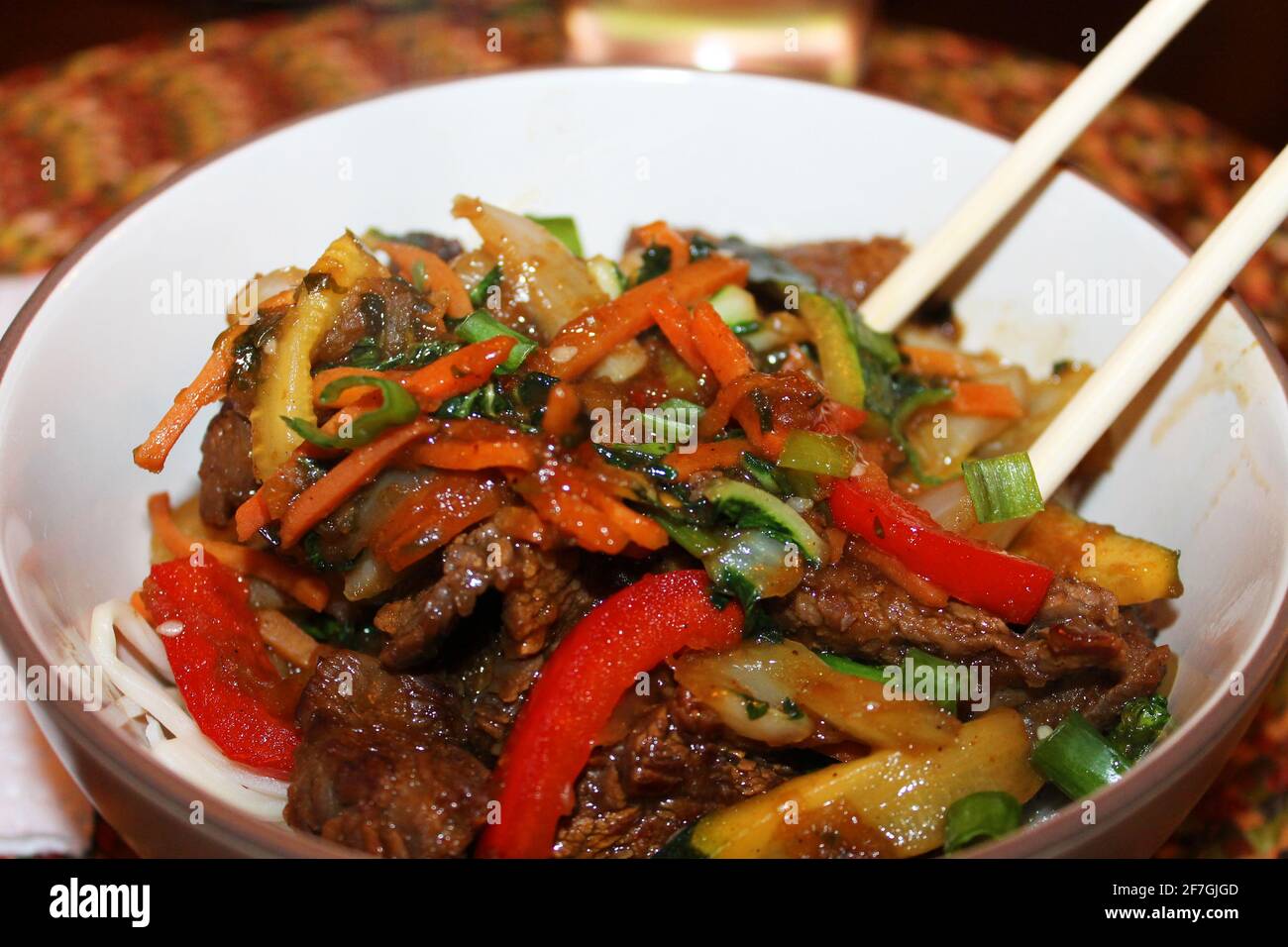 A close-up of the Korean beef stir-fry, Bulgogi, in a bowl, with chopsticks. Stock Photo