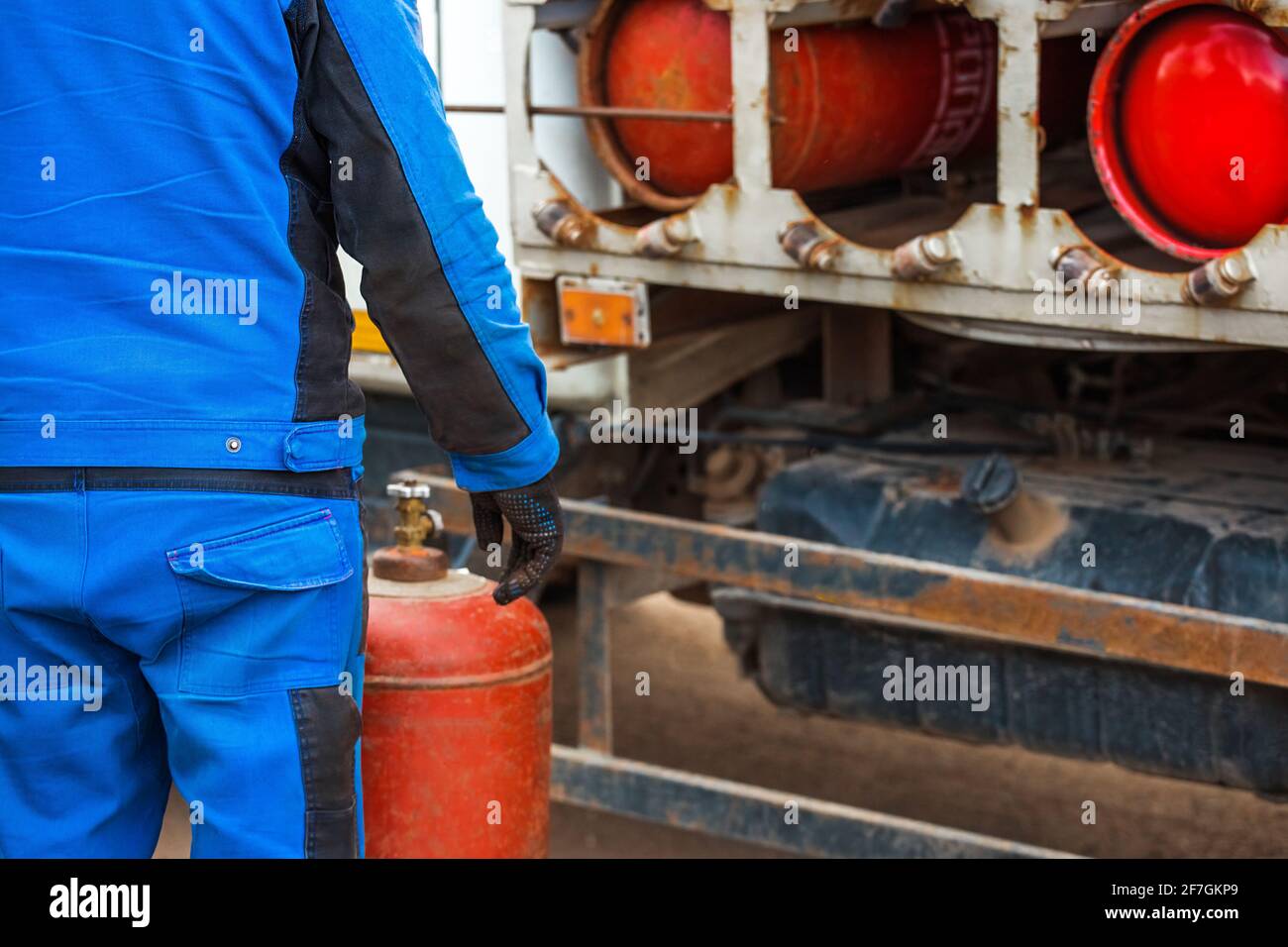 Male industrial worker puts a gas cylinder into a gas machine. Equipment for the safe transportation of propane gas bottles. Stock Photo